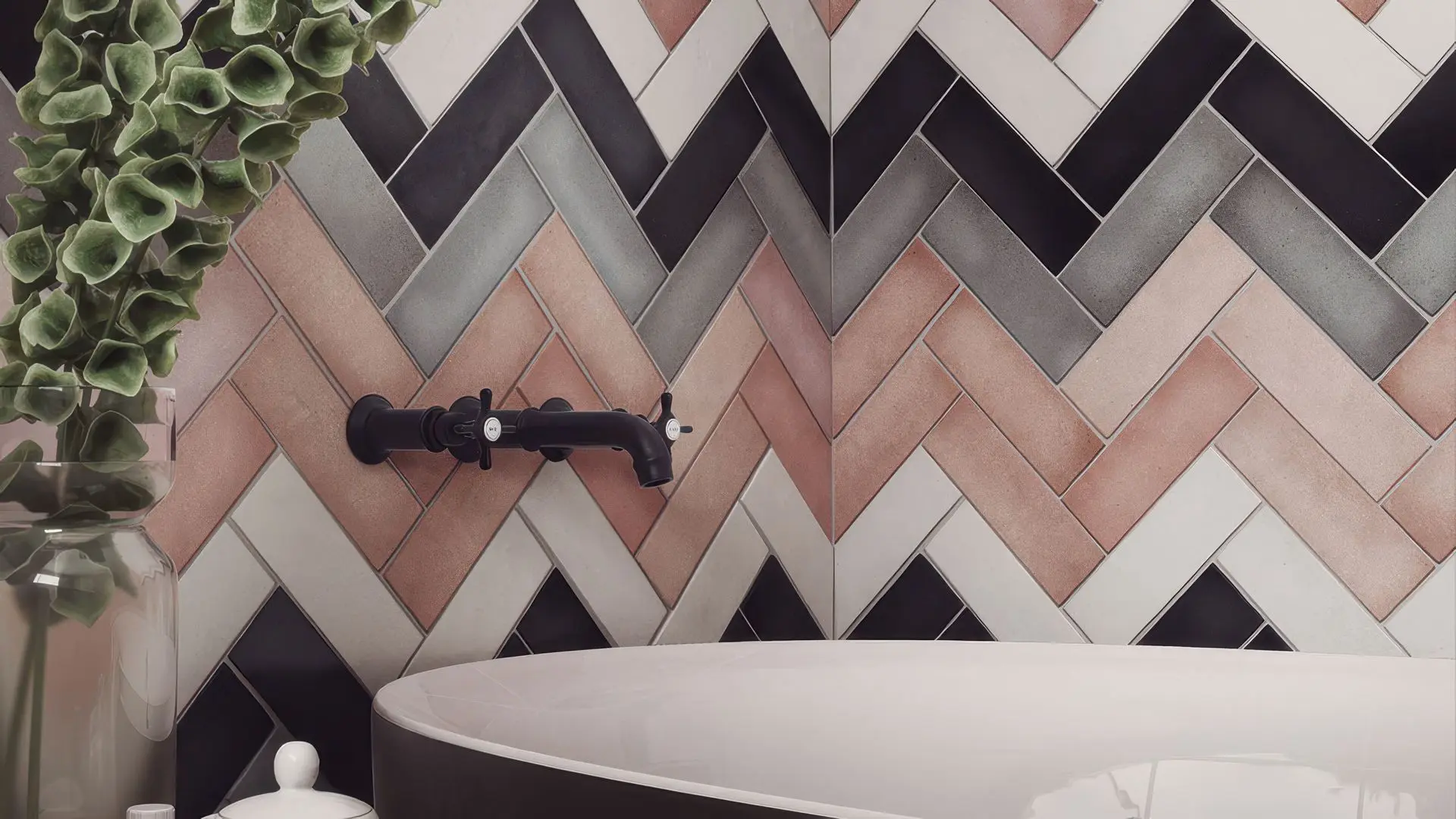 Close-up of a tub against a bold wall of black, grey, white, and rose subway tiles in a chevron pattern, experimenting with color combinations.