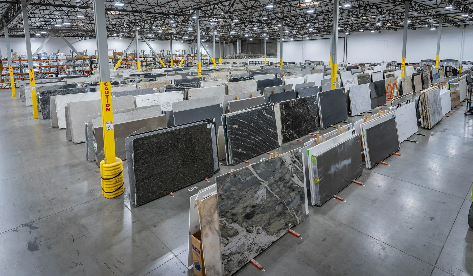 Large natural stone slab inventory displayed in rows at a Nova Tile and Stone warehouse showroom